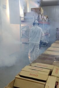 Aplicador realizando fumigação de ambiente de produção de alimentos.